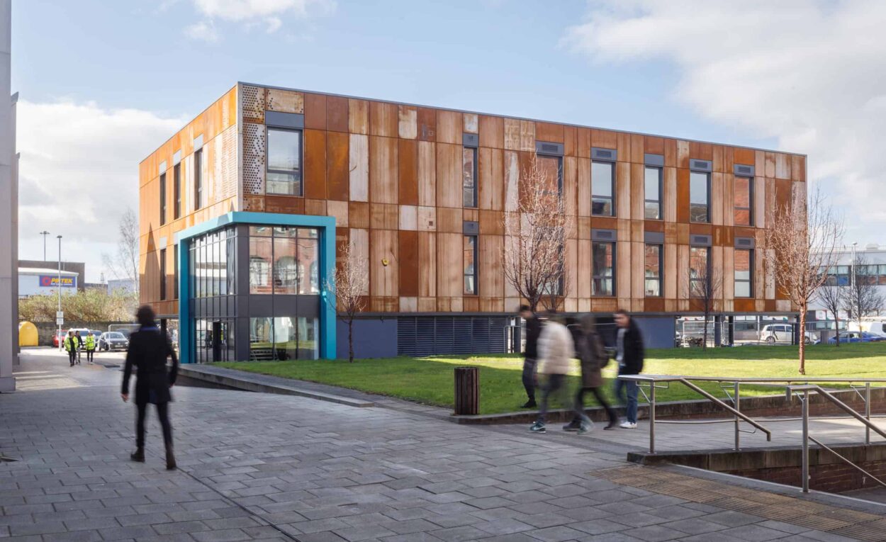 Full outside view of modular school building built for Leeds City College, with students walking around campus.